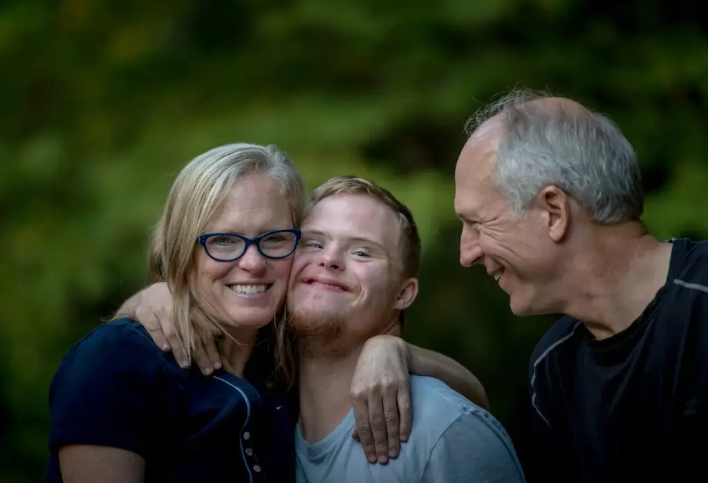 Young man embracing an older woman and man outdoors