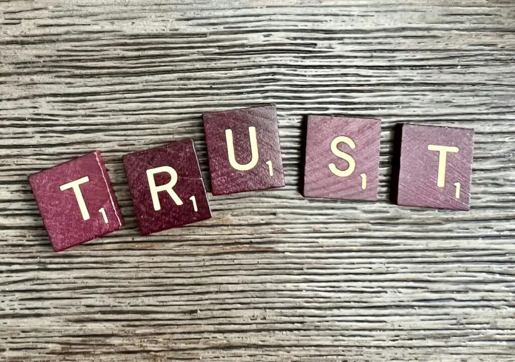 Letter tiles spelling TRUST on a wooden surface