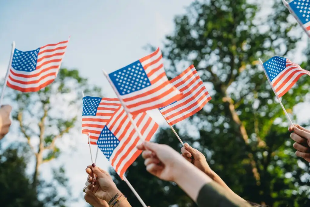 Hands waving small American flags outdoors