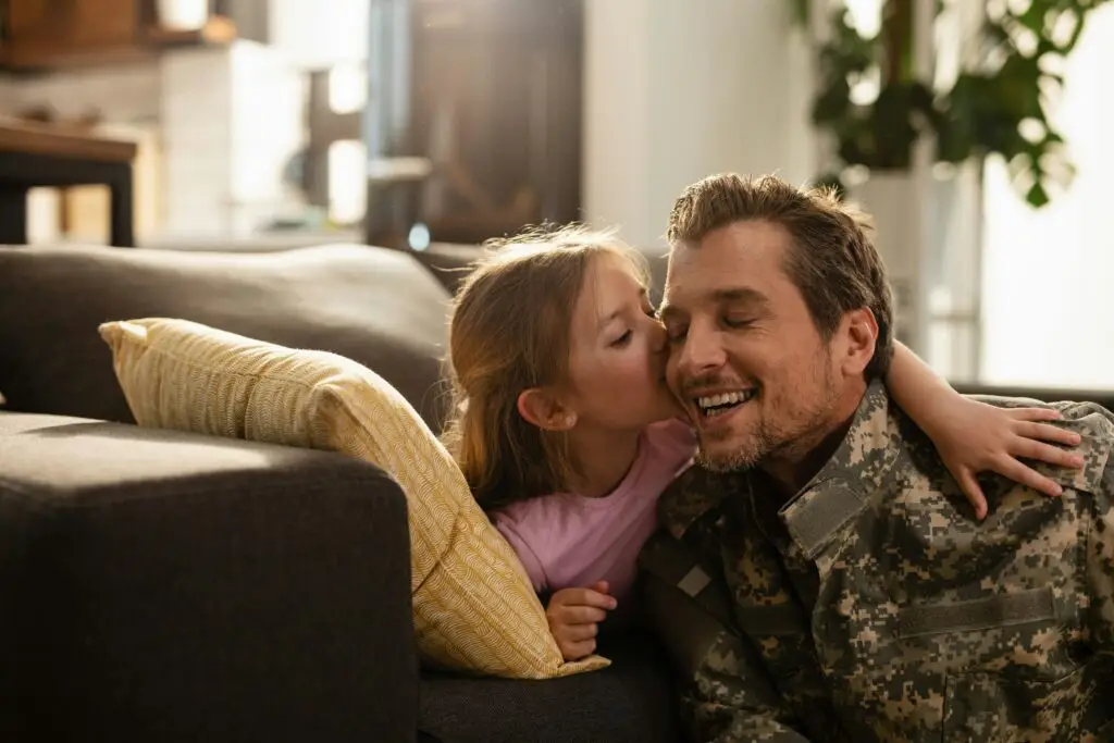 Girl kissing a man in military uniform on a couch