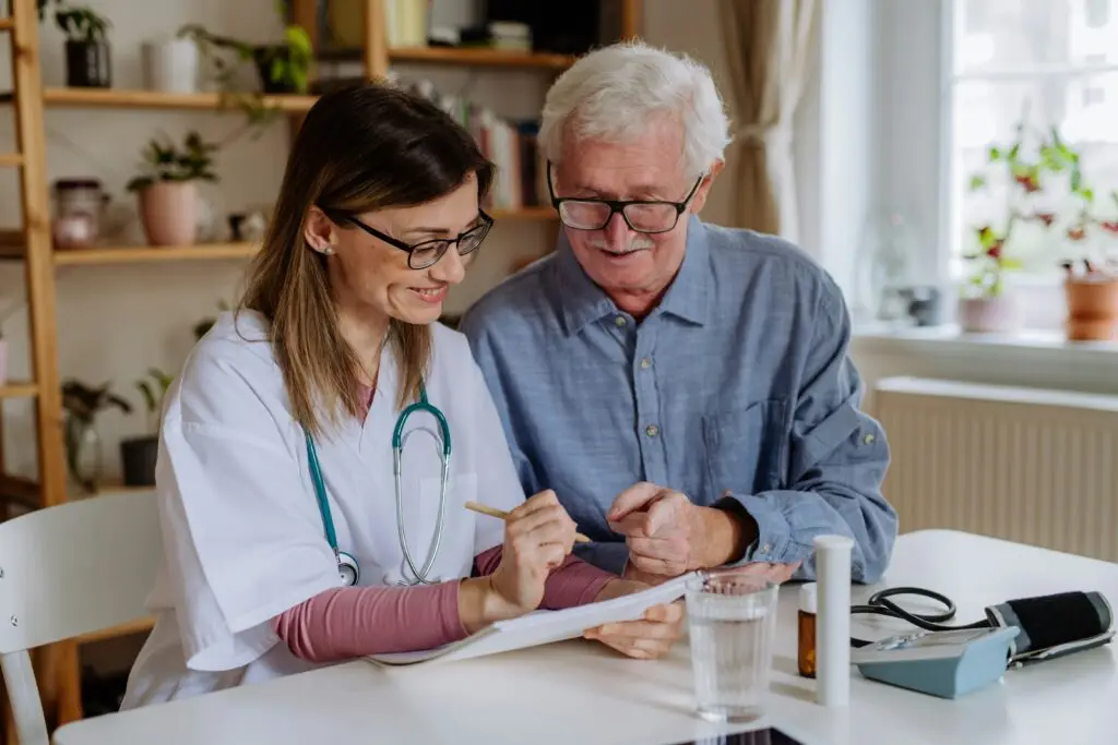 Healthcare worker and an older man reviewing paperwork at a table