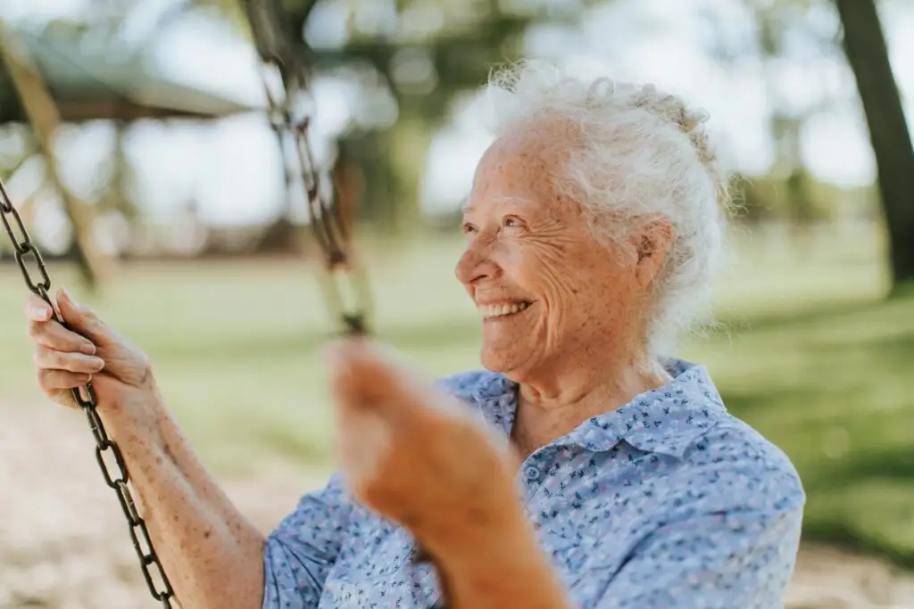 Older woman smiling on a swing outdoors