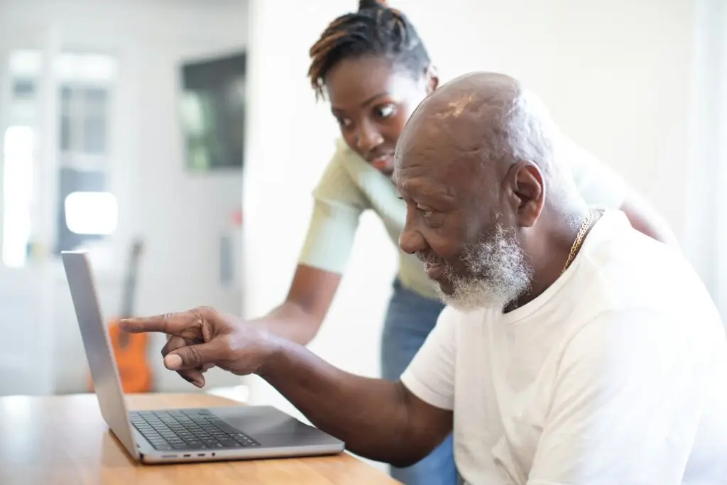 Woman pointing at a laptop screen while an older man looks on