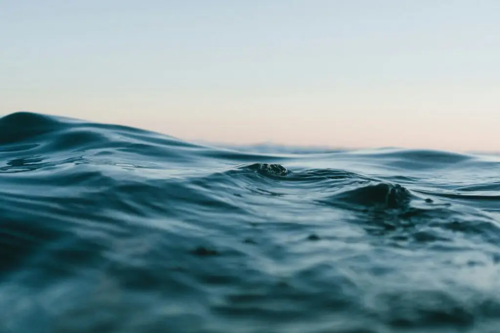 A close-up view of gentle ocean waves under a calm sky during sunset.