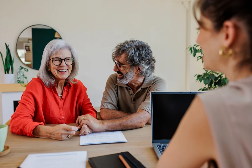 Older couple smiling and talking with a woman across a table