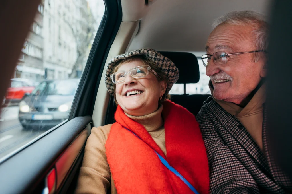 Older couple smiling in the back seat of a car
