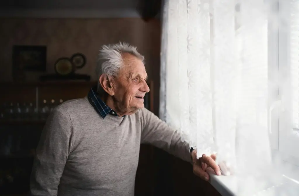 Older man smiling and looking out a window
