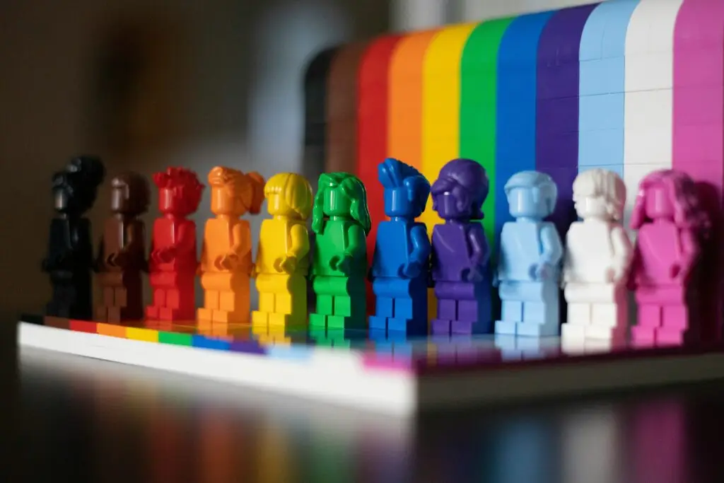 Rainbow-colored toy figures lined up in front of a matching rainbow backdrop