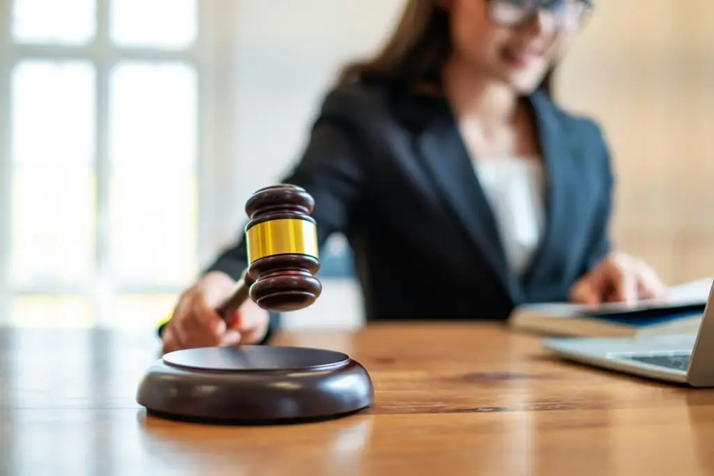 Person at a desk holding a gavel above a sound block