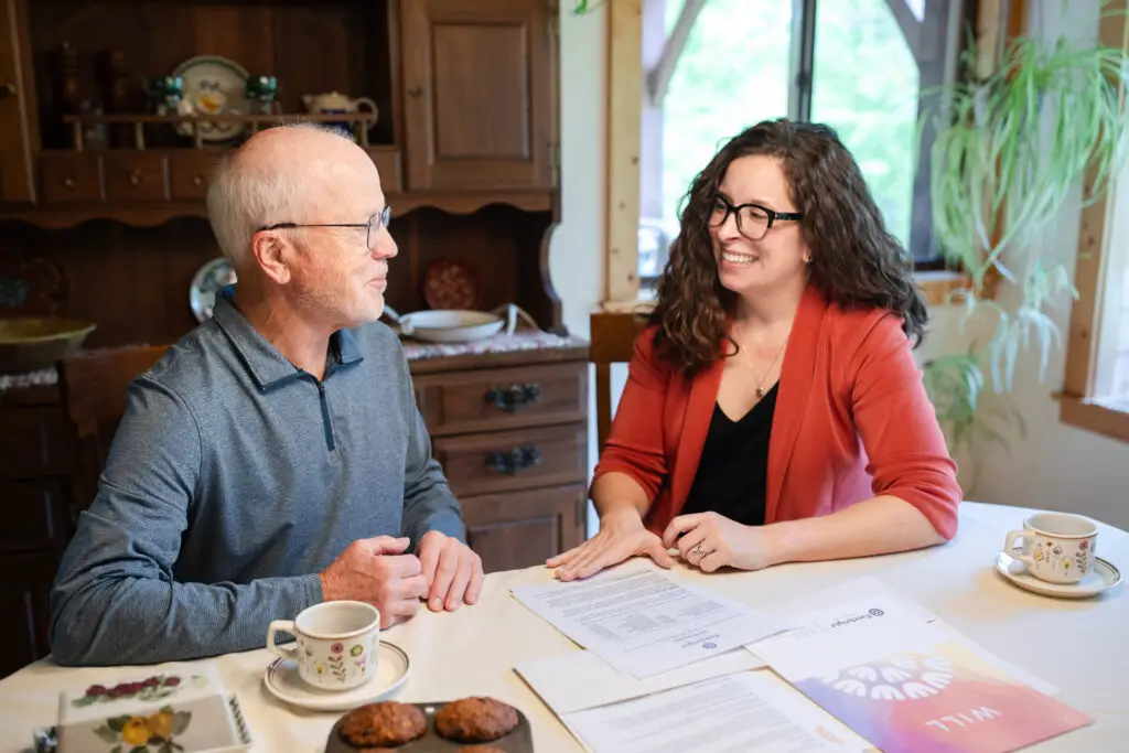 Erick Larson and Lauren Fink talking at a kitchen table with papers and coffee