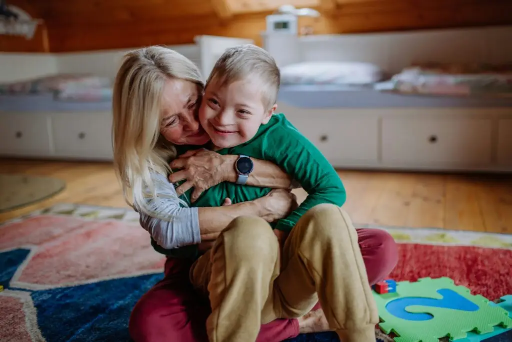 Grandmother hugging a smiling young boy on a play mat