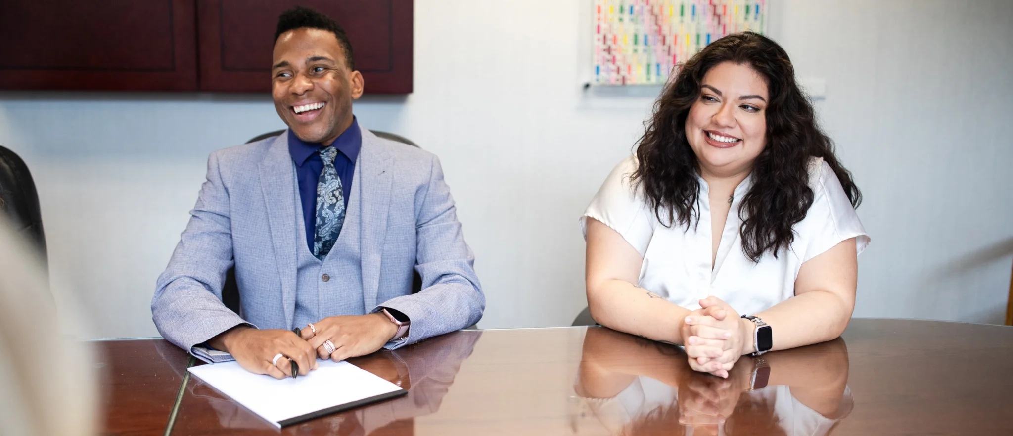 Joshua Perry-Barnes and Michelle Zavala smiling at a conference table