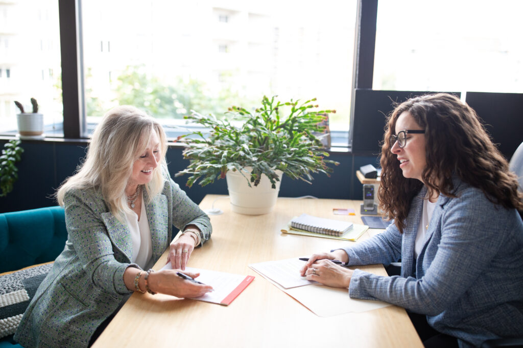 Two women reviewing documents at a desk in the Everbright Legacy Law office