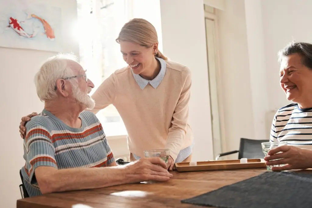 Young woman laughing with two older adults at a table