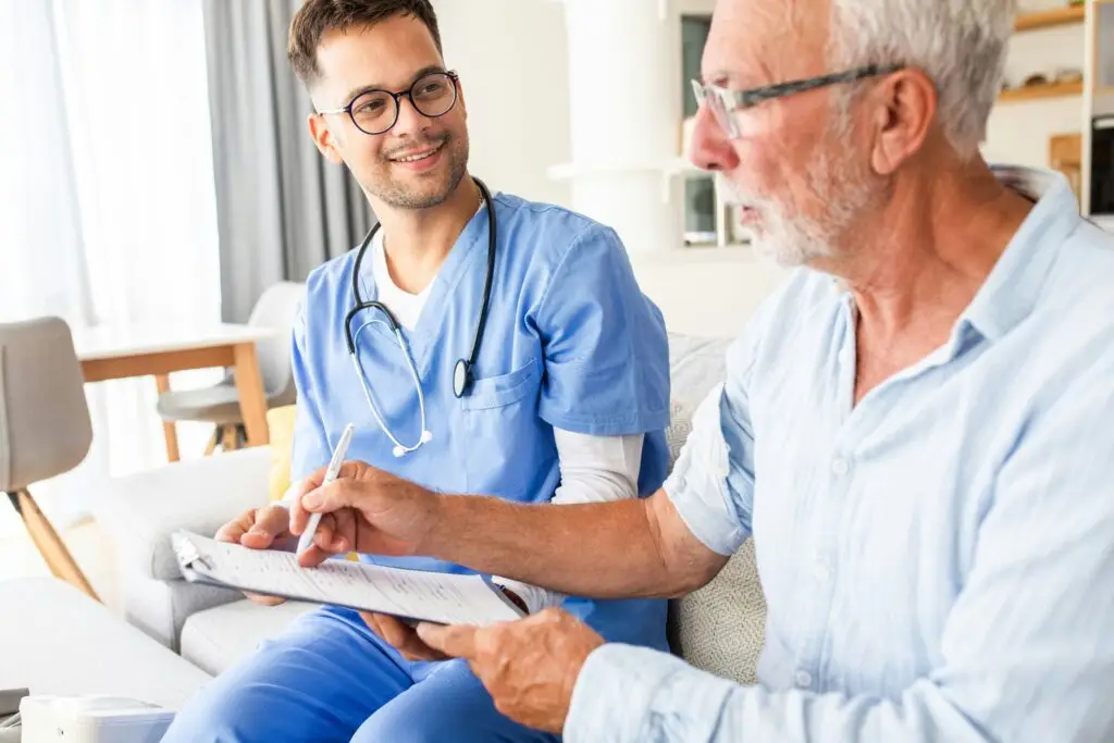 Healthcare worker helping an older man fill out a form on a clipboard