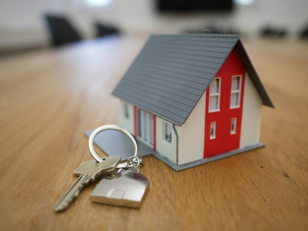 A small model house with a red door sits on a wooden table next to silver keys on a house-shaped keychain, symbolizing the importance of Minnesota elder law in life care planning for seniors.